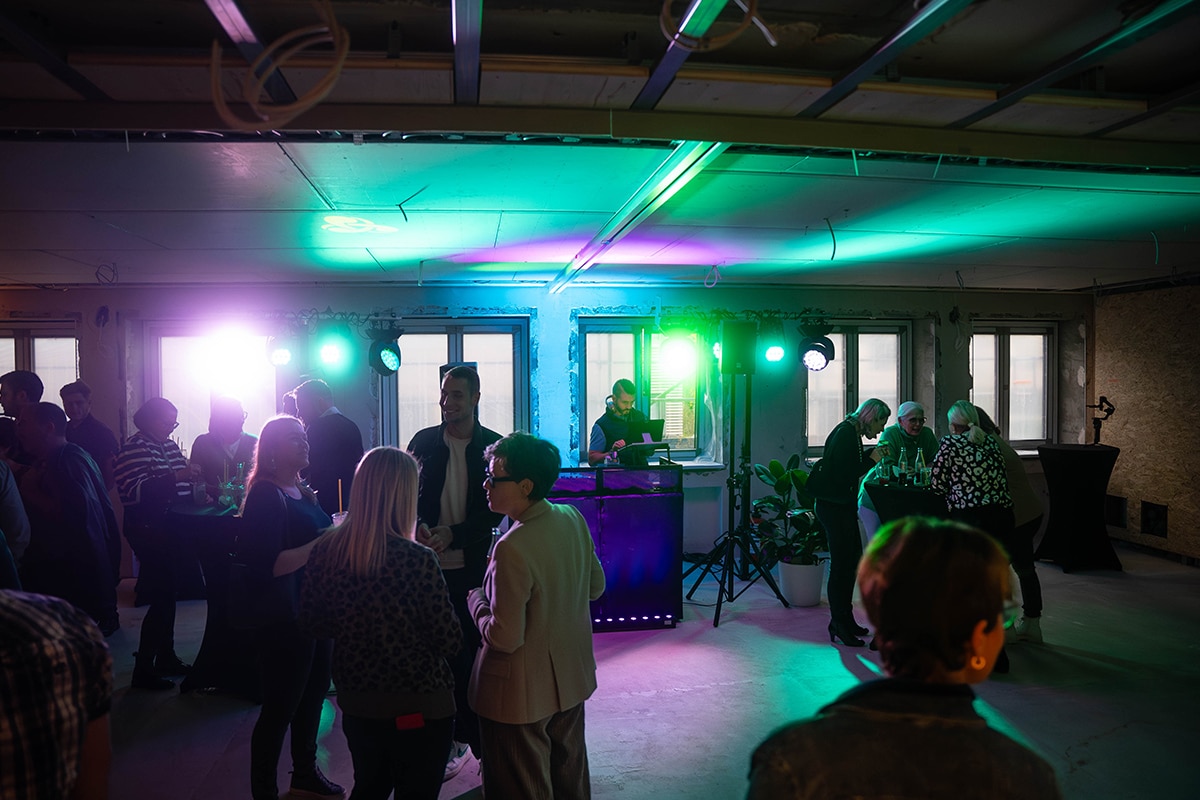 Zusammenkunft von Mitarbeiter:innen in entspannter Umgebung mit DJ und Lichttechnik.