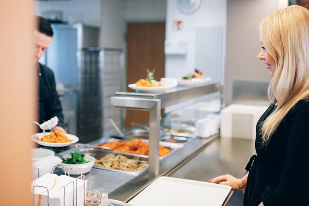 Eine Frau holt sich Ihr Mittagessen in der Betriebskantine.